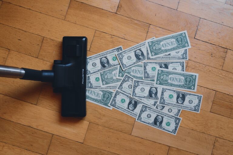 A vacuum cleaner going over a pile of $1 bills on the floor.